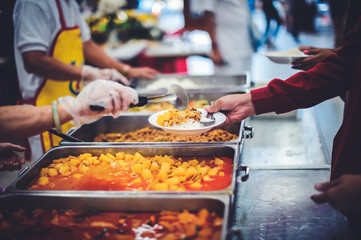 Volunteers help to draw food for the poor who are waiting to receive food in hunger.