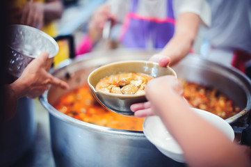 The donor gives warm food to the poor, concept of sharing food to the poor