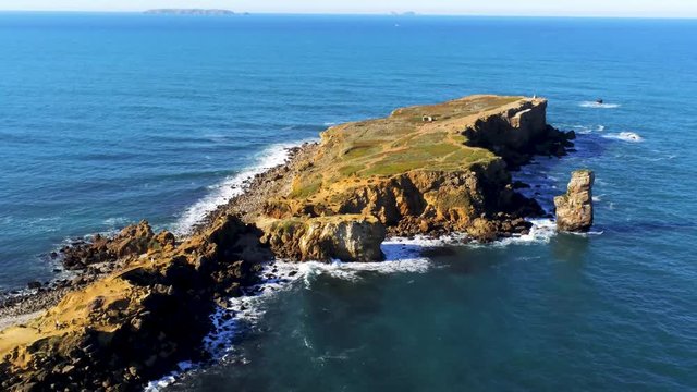 aerial view (zoom out) of the  papoa peninsula in Peniche, Portugal. Sea waves, white foam and impressive cliffs.