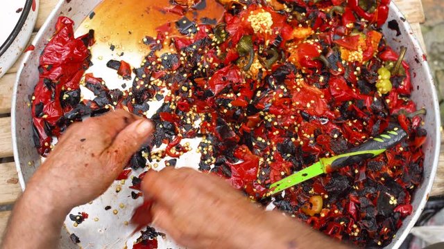 Cleaning grilled red peppers with a knife and hands. First person view from above. Speed up video