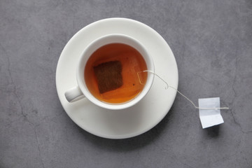 tea bag in hot water of ceramic cup on black stone table.