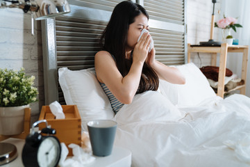 illness woman feeling unwell and sneeze on bed.