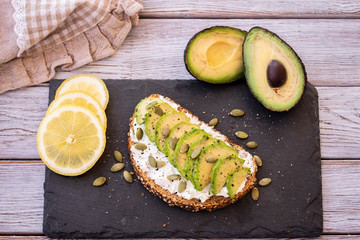 Light break or lunch concept. Fresh healthy whole grain bread sandwich with cheese and avocado on a wooden rustic table