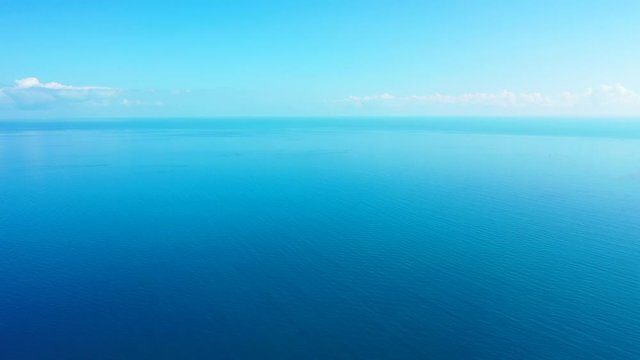 Peaceful sea scenery with endless blue water of calm ocean surface under bright sky with shiny white clouds in Caribbean