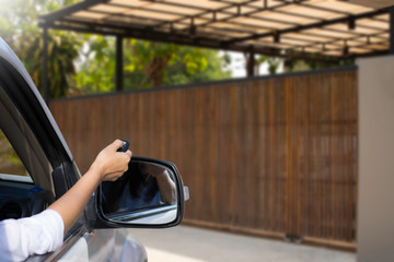 Woman in car, hand using remote control to open the automatic gate when driving and arrive home....