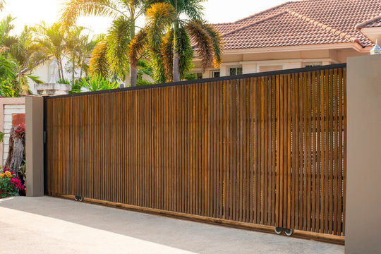 Electric automatic wooden door or garage with modern home background. Auto gate and remote control concept.