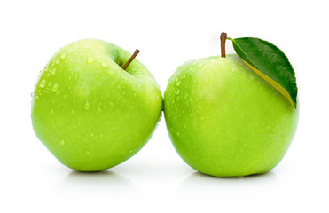 two green granny smith apples with water drops and green leaf isolated on white background .