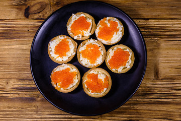 Tartlets with red caviar on a black plate. Festive food. Top view