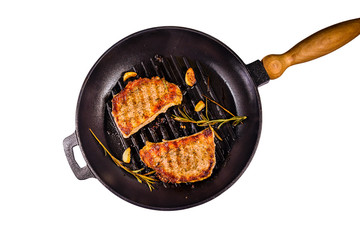 Roasted steaks with garlic, rosemary and spices in cast iron grill pan isolated on a white...