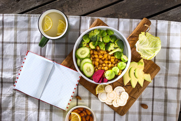 Open notebook with blank pages with plate of fresh vegetarian food top view. Balanced diet food