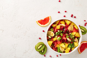 Mixed fruit salad in plate on light background top view Diet summer food concept