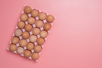brown eggs in egg box on pink background