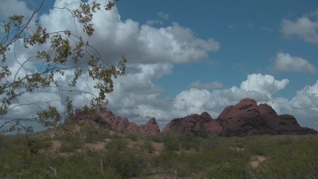 Papago Buttes. Clouds over the buttes--big and small--at Papago Park, Phoenix AZ. A creosote bush blows in the breeze in the foreground.