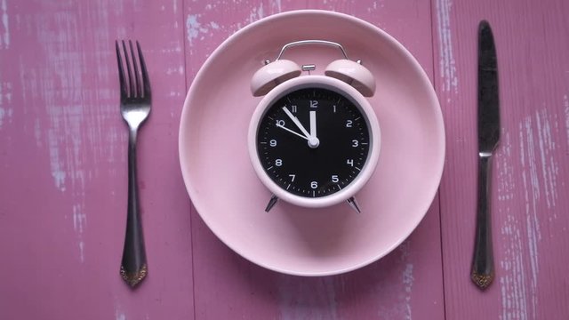 alarm clock on plate pink background 
