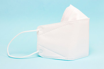 Protective white mask on a blue background, close up, side view