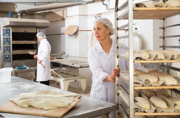 Woman pushing rack trolley with shaped raw dough