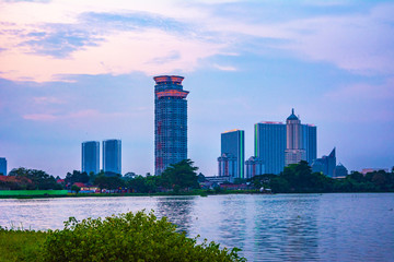 Fototapeta premium Tangerang, Indonesia - 5th January 2018: A view of Danau Kelapa Dua (Kelapa Dua Lake) on the foreground and Lippo Karawaci district buildings in the background. Taken in a cloudy afternoon.