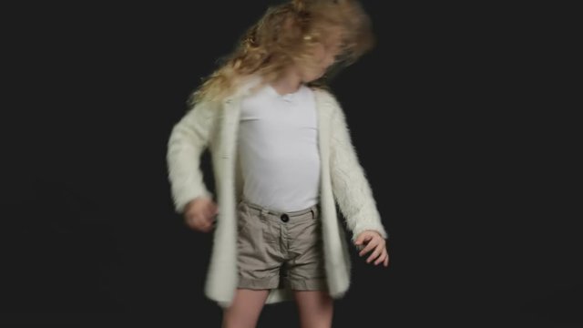 Little girl with blond curly hair, white shirt and white knitted jacket