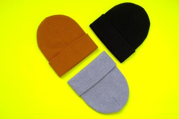 Beanie hat.Hat set on a bright yellow neon background. Fashion accessory. Warm clothes. Brown, black, gray hat