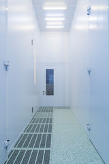 Inside white sterile clean room .Hallway with raised floor and door in clean room for pharmaceutical or electronic semiconductor industry.