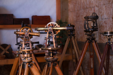 Two antique surveyors sextants on wooden tripods in workroom environment with tripod stands in...