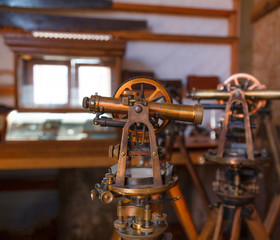 Two antique surveyors sextants on wooden tripods in a workroom environment