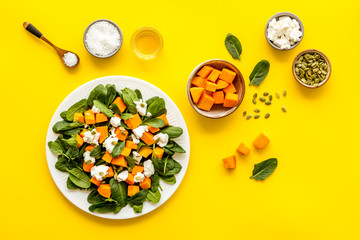 Cooking salad with pumpkin and basil. Ingredients on yellow background top-down