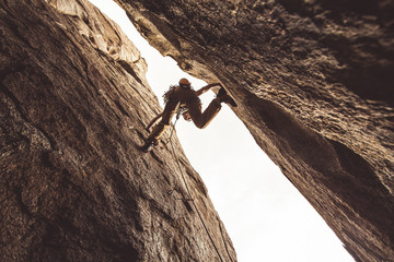 Rock climber in a canyon, pressing between two walls.