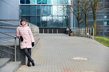 Street photo of a pretty Caucasian woman in a pink jacket on a spring day