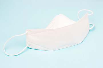 White mask on blue background, concept of protection against dirty air