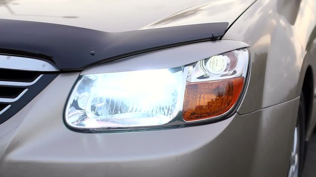 Close-up of the car included fog lights. Slow motion. Headlights in the car, close-up. Close-up of the white light of the headlight on the car.
