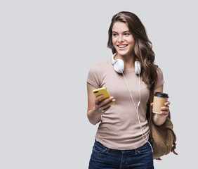 Young beautiful woman with smart phone studio portrait, smiling student girl going on a travel isolated on gray background	