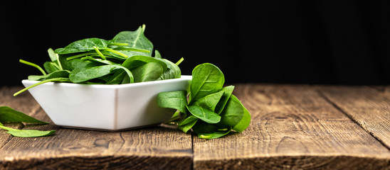 Old wooden table with fresh Spinach (selective focus; close-up shot)