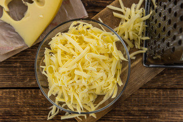 Wooden table with grated Cheese (close-up shot)
