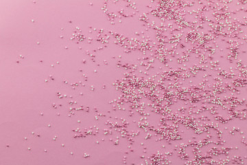 Sprinkle background with pink and white cake topping sprinkles scattered on pale pink backdrop with space for text