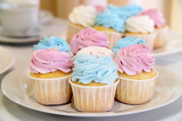 Mini cupcakes with whipped cream decorated with spring and Easter candy sprinkles. Additional cupcakes blurred in the background.
