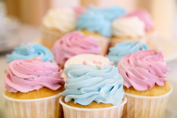 Mini cupcakes with whipped cream decorated with spring and Easter candy sprinkles. Additional cupcakes blurred in the background.