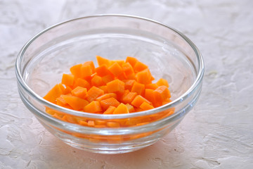 finely chopped carrots in a glass cup on a gray background