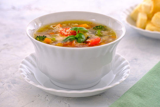 Hot and fragrant Italian ministrone soup with cherry tomatoes, basil and parmesan in a white cup