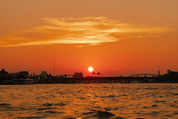Naklejka premium Sunrise or sunset view of Chao Phraya River , Bangkok, Thailand . Shows water transport. reflective of the sun. Image contain certain grain or noise and soft focus