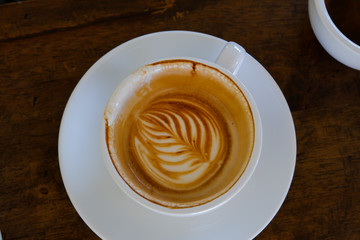 Close up Coffee latte art white cup. Coffee was eaten until the bottom of the cup. on wood table at coffee cafe .