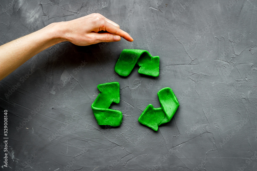 Wall mural Recycling symbol - composition with hands - on grey background top-down copy space