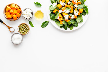 Salad with pumpkin and basil - near ingredients - on white background top-down copy space