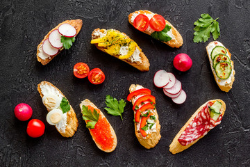 Sandwiches - set with vegetables, caviar, salami - on black background top-down