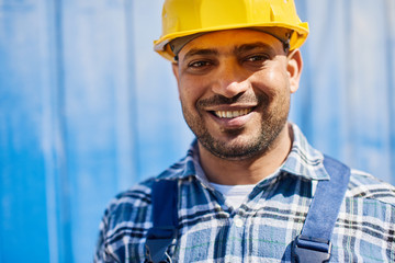 Smiling engineer in yellow construction helmet looks at the camera.