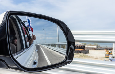 Car mirror with reflection of the road and the Russian flag