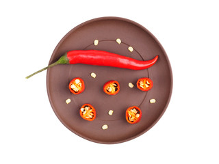 Red chili on brown clay plate isolated on white. Indian cuisine, ayurveda, naturopathy concept