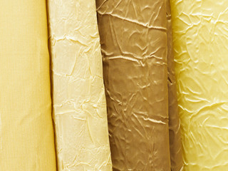 Yellow and brown color fabrics hang for sale in a store. The concept of fashionable clothes and interior