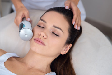 Beautiful young woman having ultrasonic facial treatment