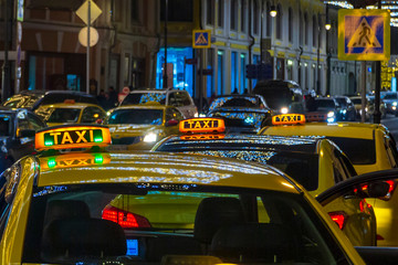 Night picture of a taxi car. Taxi sign on the car roof glowing in the dark